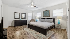 A bedroom with a bed, dresser, ceiling fan, and two wall-mounted mirrors. - Cozy Downtown Home W/ Beautiful City Views! (Houston)