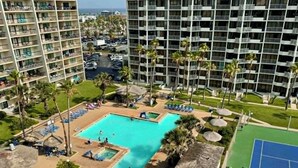 A hotel with a swimming pool, tennis court, and multiple balconies. - Saida IV Condos - S4904 (South Padre Island)