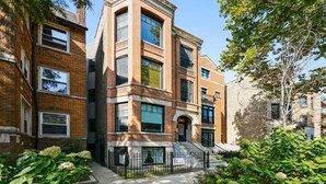 Un immeuble à plusieurs étages, doté de façades en briques, de grandes fenêtres et d’une entrée centrale avec des marches.
