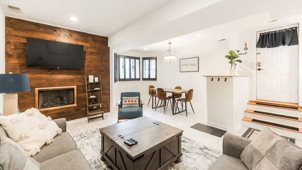 Un salon moderne avec une cheminée, un canapé, une table basse, un téléviseur et un coin repas.