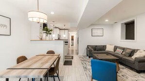 Un salon moderne avec un canapé, une table à manger et un coin cuisine à l’arrière-plan.