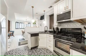 A modern kitchen with white cabinets, a black stove, and pendant lighting. - Serene 2-bedroom condo with AC in vibrant Chicago (Chicago)