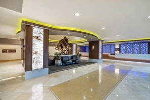 Un moderno vestíbulo de hotel con un mostrador de recepción, zona de estar y una gran escultura decorativa.
