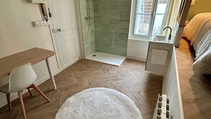 A bathroom with a shower, a sink, and a window.