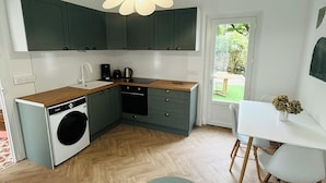 A modern kitchen with a built-in washer, a dining area with a table and chairs, and a view of the outdoors.