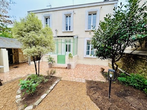 Un bâtiment doté d’une cour pavée de pierres, d’une porte verte et de plantes en pot.