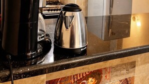 Eine Küche mit Herd, Wasserkocher, Kühlschrank und Kaffeemaschine.