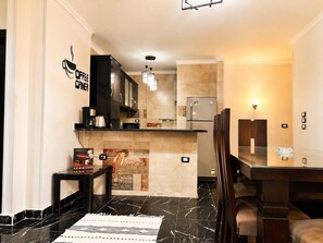 Eine moderne Küche mit integrierter Espressomaschine, einem Kühlschrank und einem Essbereich mit Holztisch und Stühlen.