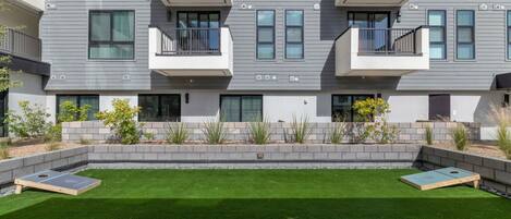 Un immeuble d’appartements moderne, doté d’un toit plat, de balcons et d’une pelouse bien entretenue agrémentée de deux jardinières en bois.