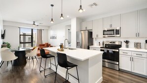 A modern kitchen with white cabinets, stainless steel appliances, and a central island with bar stools. - Arcadia Oasis w/ Resort Pool, Gym & Fire Pits (Phoenix)