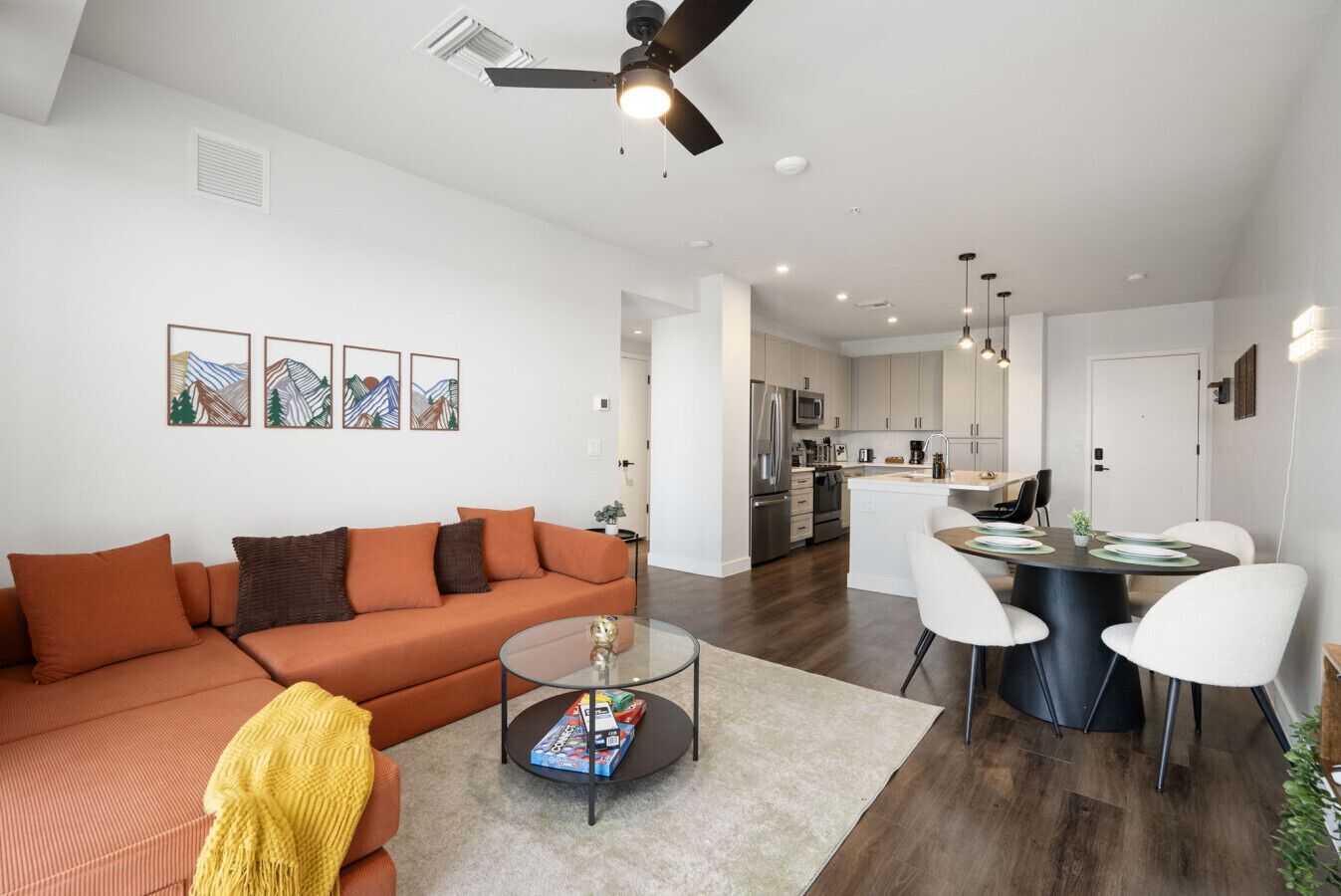 A modern living room with a sofa, coffee table, and dining area with chairs.