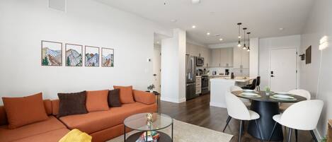 A modern living room with a sofa, coffee table, and dining area with chairs.