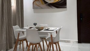 Ein Essbereich mit Deckenventilator, Tisch und Stühlen sowie einem an der Wand befestigten abstrakten Gemälde.