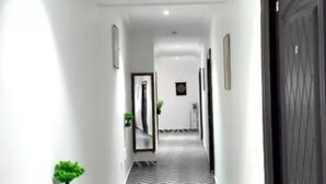 A hallway with a chevron-patterned floor, white walls, and a dark door.