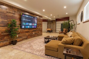 A living room with a flat-screen TV, a brown sofa, a coffee table, and a potted plant. - Private Forest Cabin: Hike, Bike, Hot Tub + Sauna, near ATV trails and lakes (Easton)
