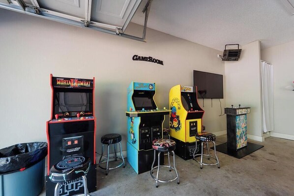 A room with arcade games, a projector, and a GameRoom sign.