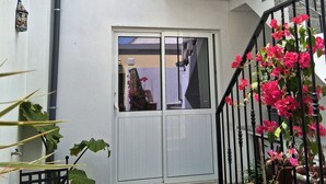 Een wit gebouw met een balkon, een trap en potplanten.