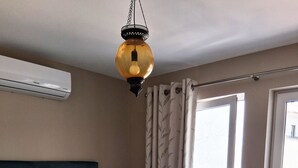 Een slaapkamer met een bed, airconditioning, een lamp en een deur.