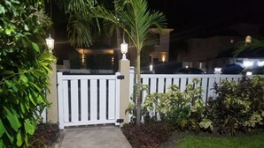 A gated entrance with a concrete pathway leading to a building, surrounded by greenery and palm trees. - Cozy St. James Beach Villa – Steps from the Ocean. (Fitts Village)