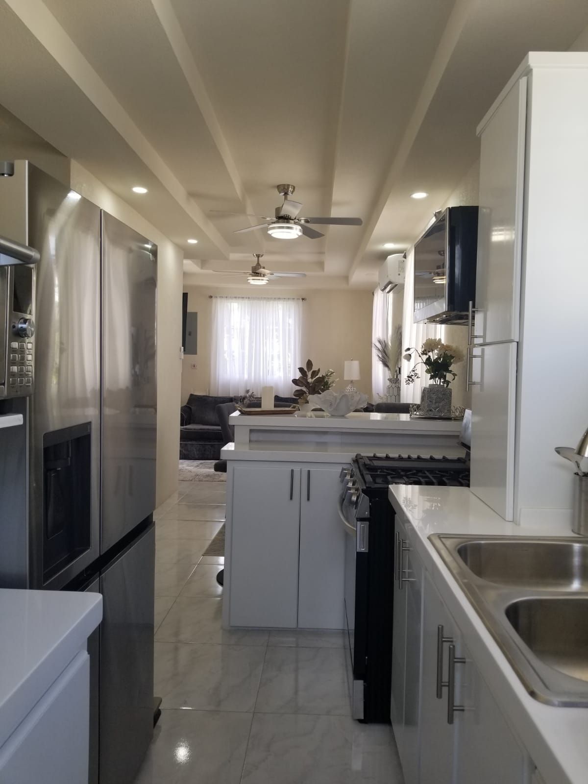 A modern kitchen with stainless steel appliances, a central island, and a ceiling fan.