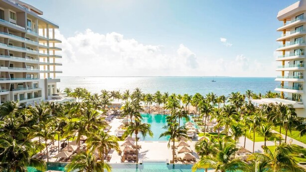 Un resort con piscina, palmeras y vistas al océano.