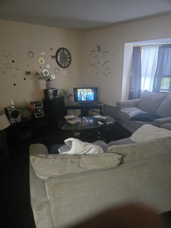 A living room with a television, sofa, coffee table, and decorative wall elements.