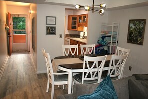 Un comedor con mesa y sillas, una cocina al fondo y un pasillo que conduce a una puerta.