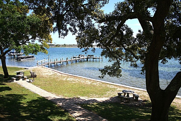 A lakeside park with a dock, picnic tables, and a grassy area.