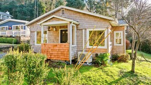 A single-story house with a porch, a small deck, and a front yard. - Steps to the Beach: Arch Cape Cozy Cottage w Sauna (Arch Cape)