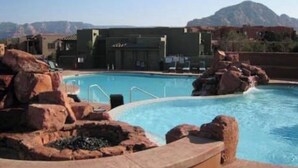 Ein Pool mit Felsformationen und einem Berg im Hintergrund.