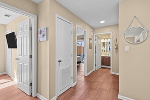 A hallway with beige walls, white doors, and a tiled floor. - New! • Sunset Palms • 2BR • 5 Min Walk to Beach! (Panama City Beach)