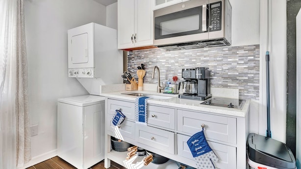 A compact kitchen with a microwave, coffee maker, and a small sink. There are cabinets with handles and a countertop with a tiled backsplash. - Cozy 1-bedroom house with AC in delightful North Port (North Port)
