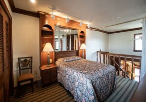 Ein Schlafzimmer mit einem großen Bett, zwei Nachttischlampen, einem Sessel, einem Spiegel und einer Treppe.