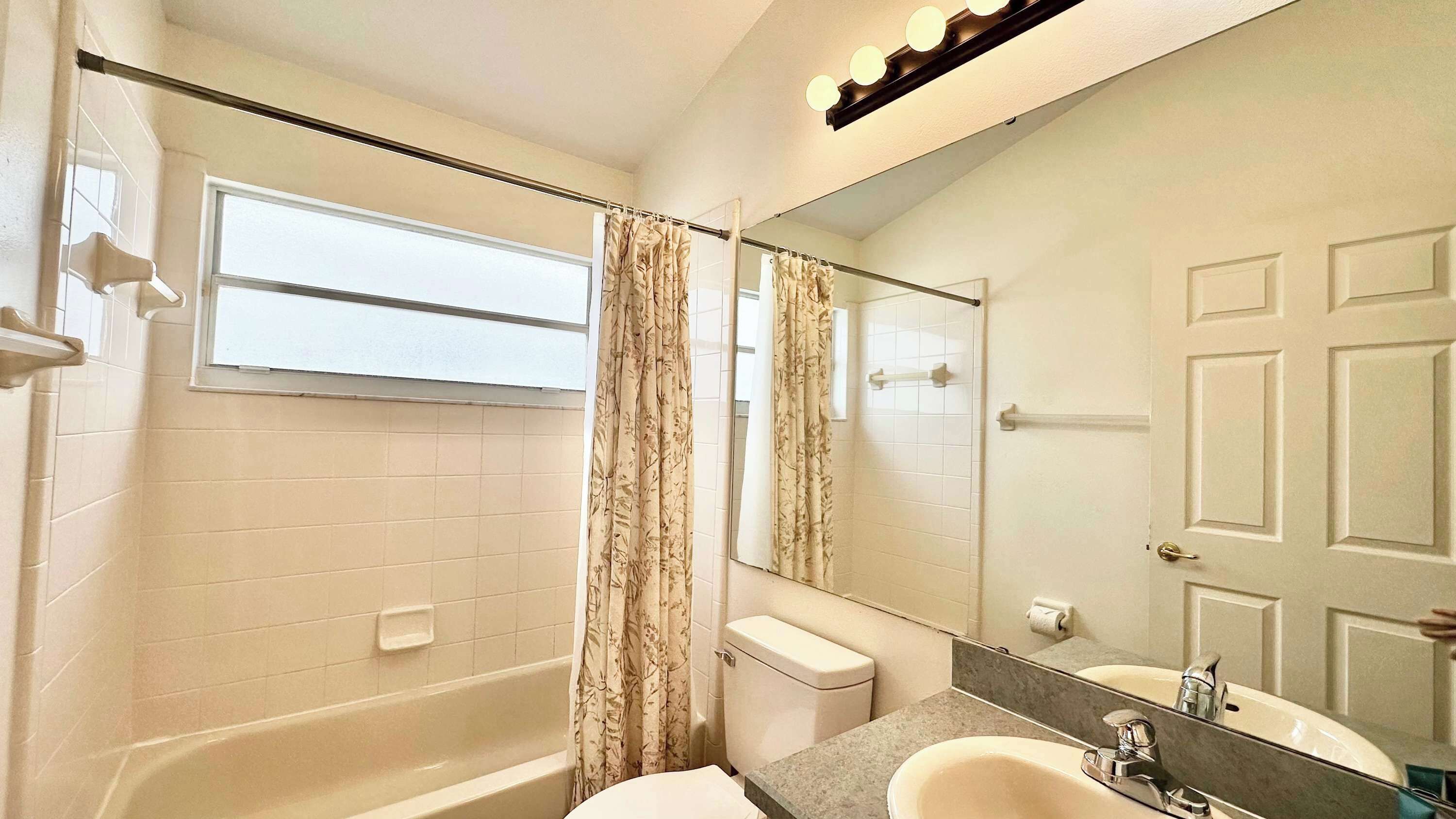 Une salle de bain avec une baignoire, des toilettes, un lavabo et un grand miroir.