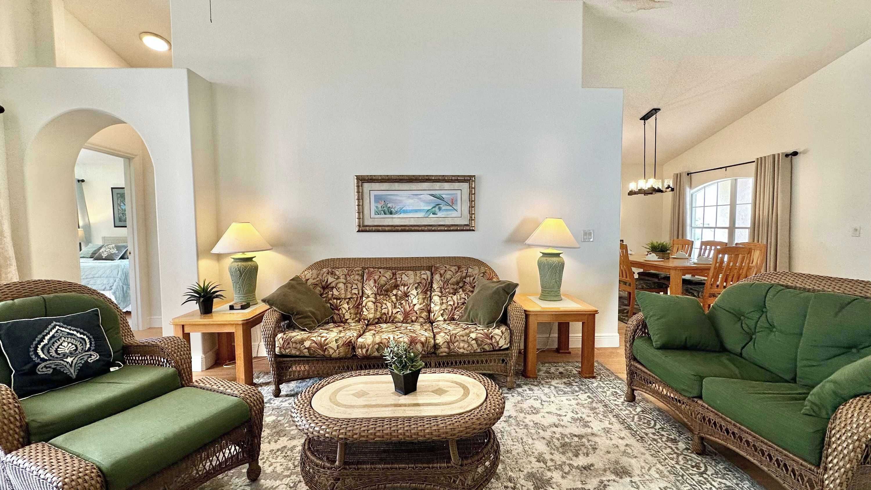 A living room with a sofa, two armchairs, a coffee table, and a dining area with a table and chairs.