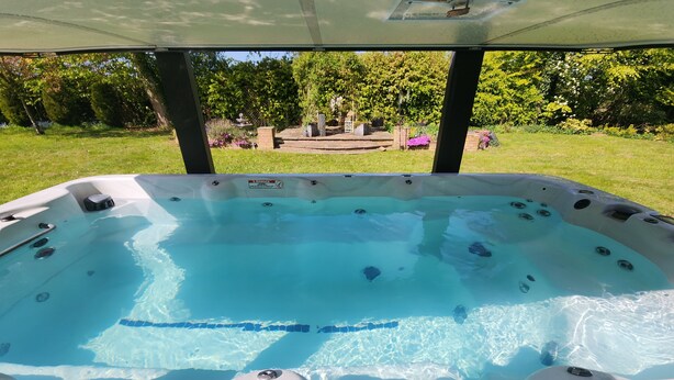 Un jacuzzi con vista despejada al jardín circundante y un pabellón al fondo.