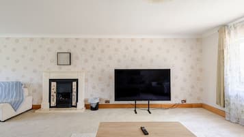 A living room with a fireplace, a television mounted on the wall, and a coffee table.