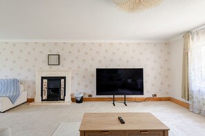 A living room with a fireplace, a television mounted on the wall, and a coffee table.