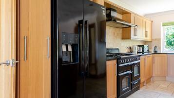 Eine moderne Küche mit einem schwarzen Kühlschrank, Holzschränken, einem Gasherd und einem Fliesenboden.