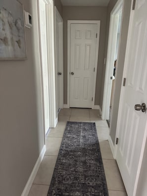 A hallway with a patterned rug, white doors, and a light-colored floor. - Quiet Canal in Ruskin on Little Manatee River with boat access (Ruskin)