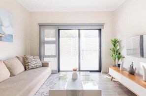 Una sala de estar moderna con un sofá, una mesa de centro y un televisor sobre un mueble de madera.