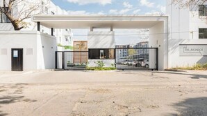 Un ingresso recintato a un edificio moderno con una passerella coperta, un cartello con la scritta 'THE MONROE' e un cielo sereno.