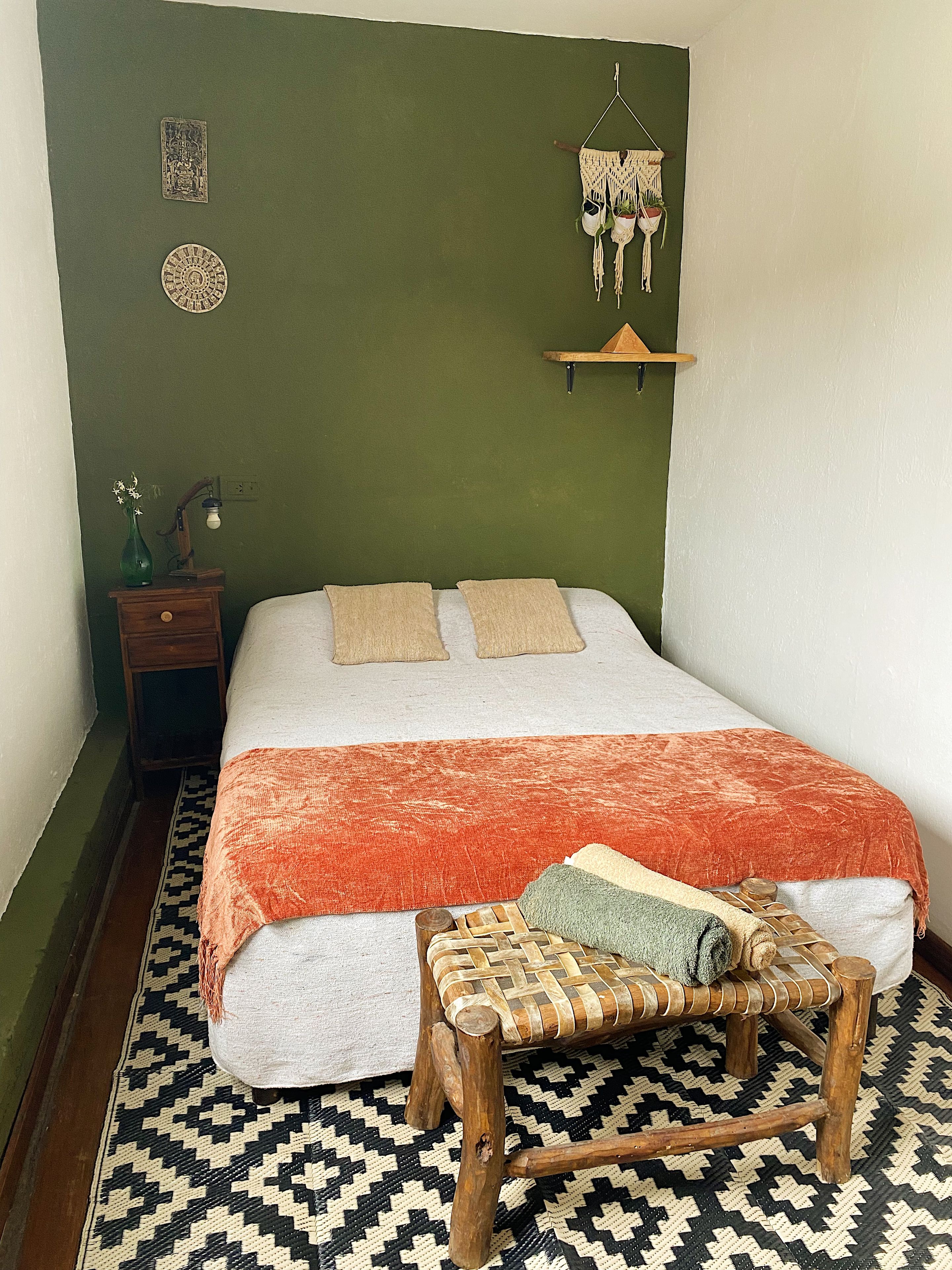 Une chambre à coucher comprenant un lit, une table de chevet, une lampe, une décoration murale et un tapis à motifs.