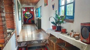 A narrow hallway with a wooden ceiling, a colorful rug, and a window with a view of greenery.