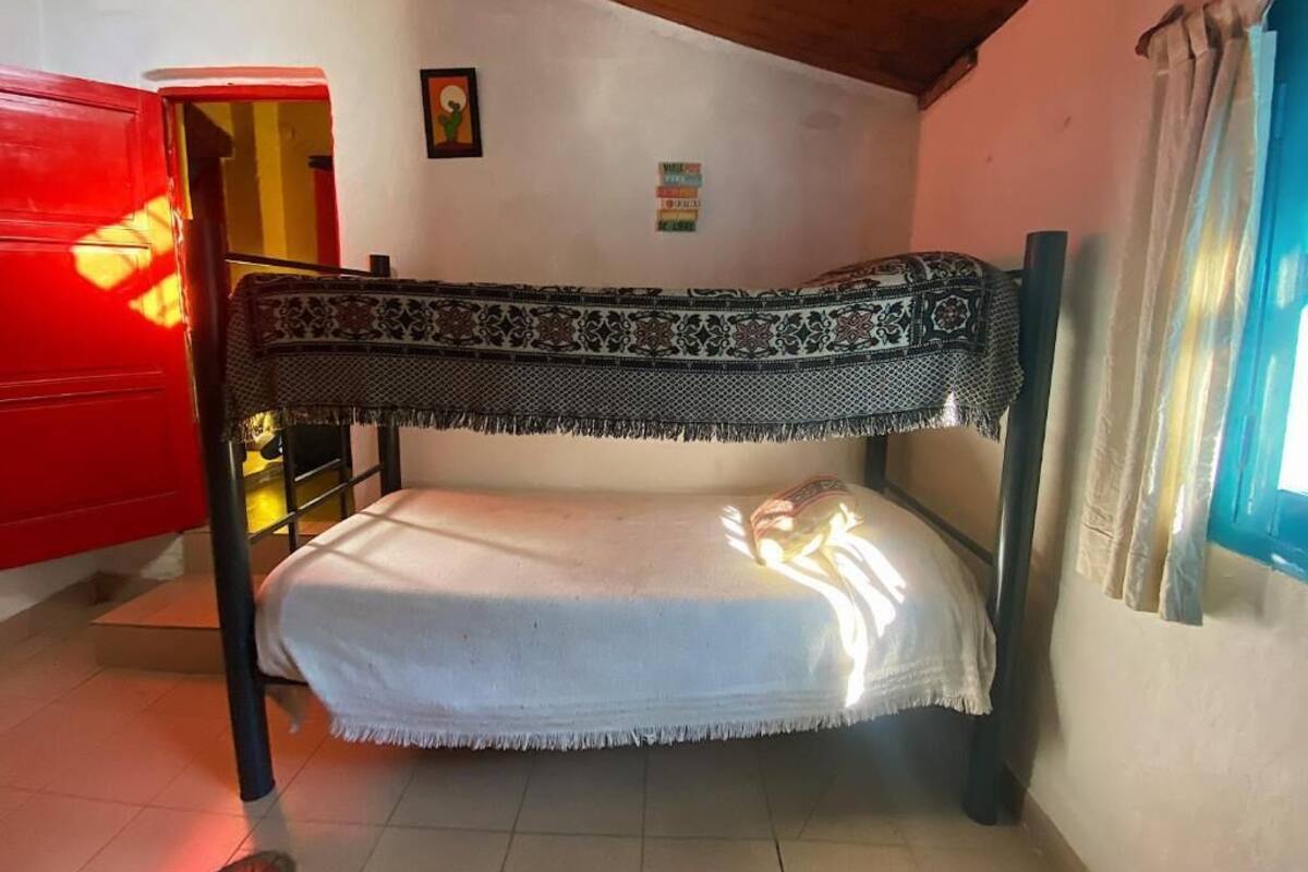 Ein Stockbett mit gemustertem Oberlauf, einer weißen Matratze und einem Fenster mit Vorhängen.