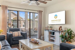 Un salón amplio con un sofá, sillones, una mesita de centro y un televisor que muestra 'Grand Welcome Branson & The Ozarks'.