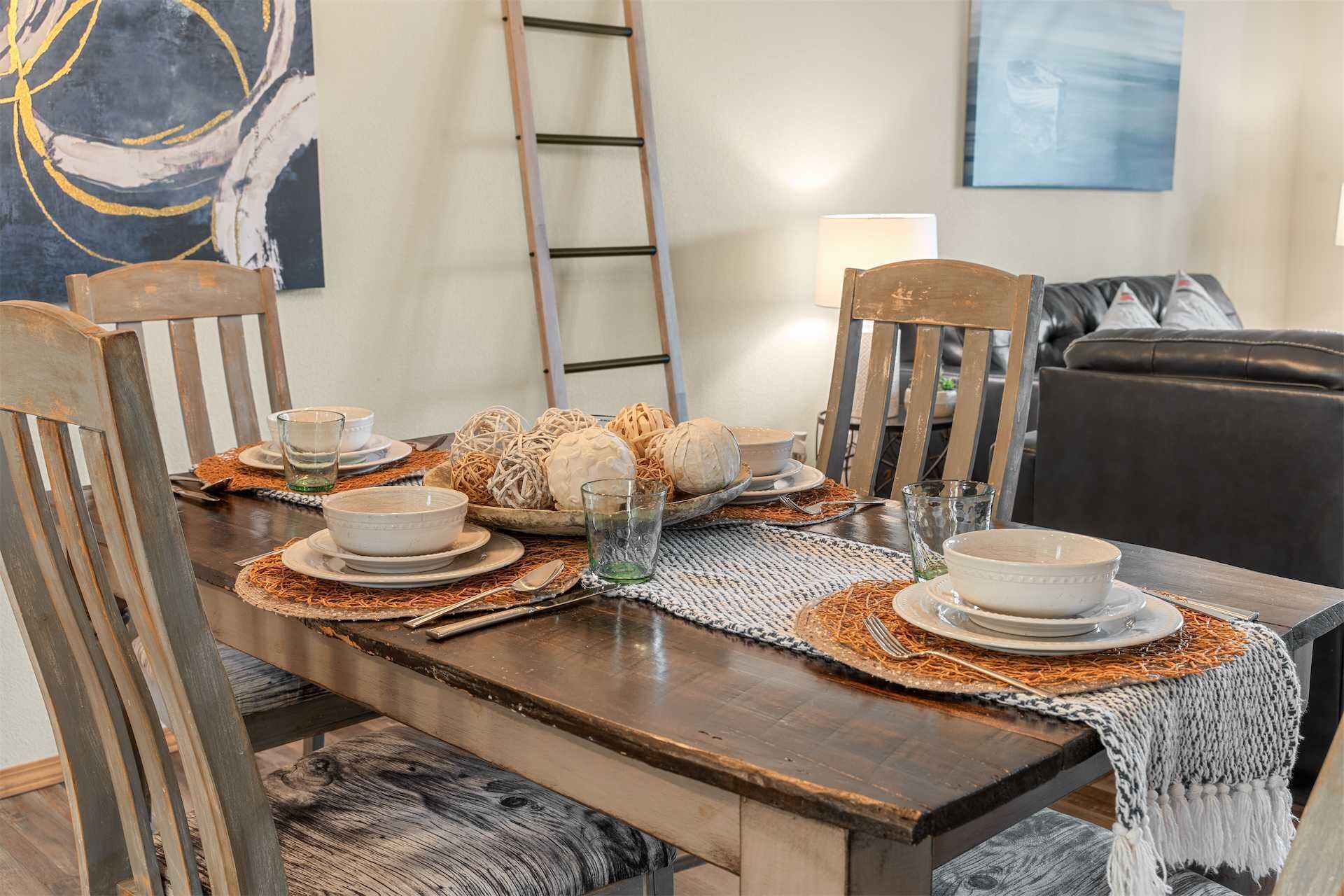 A dining table set with plates, bowls, and glasses, surrounded by chairs.