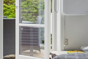 A room with a window, a white wall, and a small table with a book. - Cozy cottage in Nykøbing Sjælland (Nykøbing Sj)
