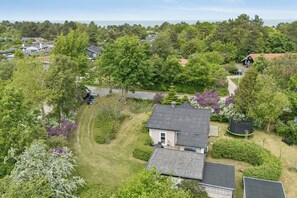 An aerial view of a residential area with houses, a grassy yard, and a trampoline. - Cozy cottage in Nykøbing Sjælland (Nykøbing Sj)