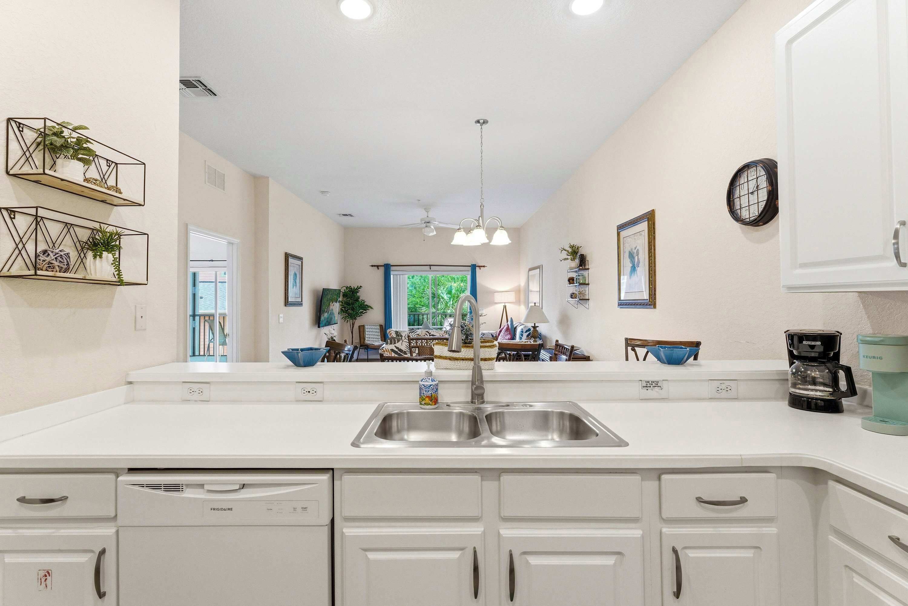 A modern kitchen with white cabinetry, a double sink, and a built-in dishwasher.